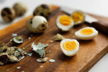 Hard-boiled quail eggs on a cutting board, partially peeled