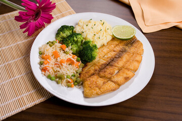 Filé de Peixe, com arroz a grega, maionese e salada de brócolis em mesa decorada. prato executivo.