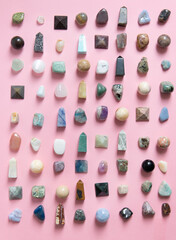 A large collection of beautiful stones. polished gems on a pink background. Geologist exposition.