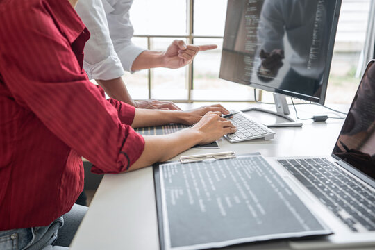 Two professional programmer cooperating and working on web site project in a software developing on desktop computer at company, codes and typing data code, Programming with HTML, PHP and javascript