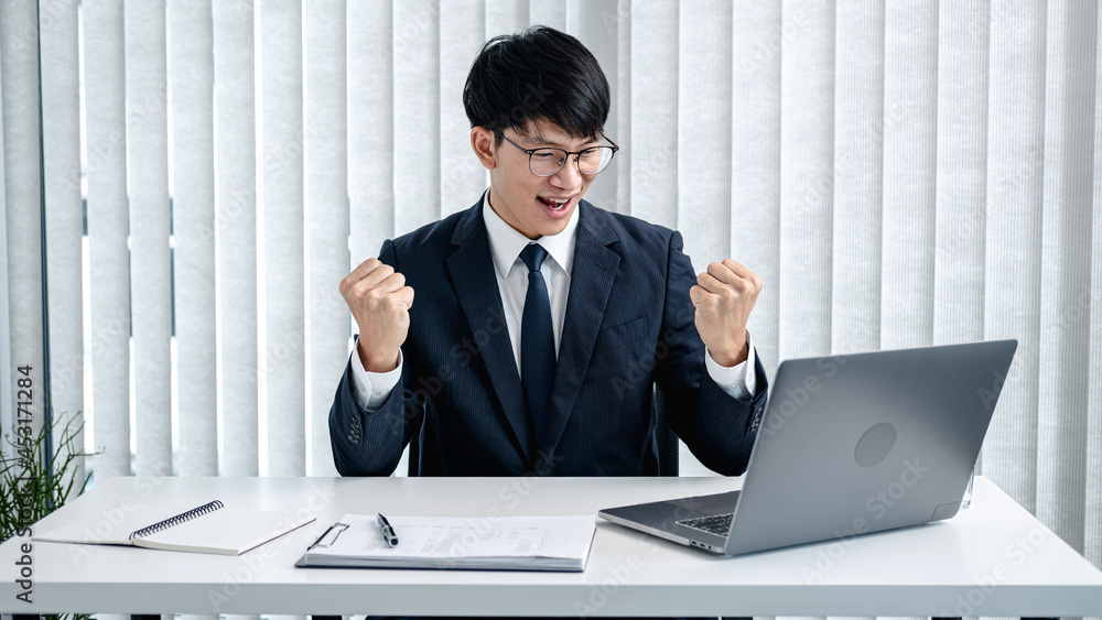 Poster businessman in suit is writing strategy on notebook and typing business report on laptop while sitti