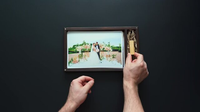 the photographer puts wedding photos and a flash drive in a box. 