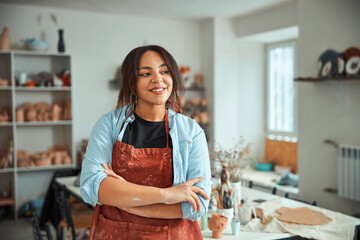 Charming female potter standing in pottery workshop