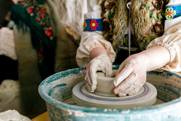 a woman in traditional Slavic clothes works on a potter's wheel