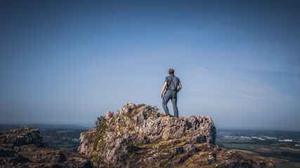 Junger Mann sieht in die Ferne auf einem Fels in Oberfranken in Bayern in Deutschland