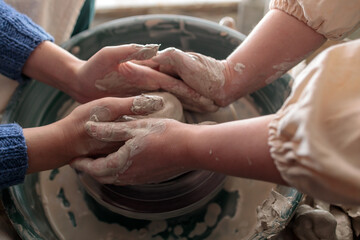 the pottery coach holds the student's hands