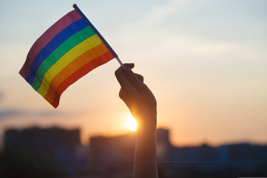 Transgender woman holding rainbow flag on sky background, LGBTQ pride, parade, march concept