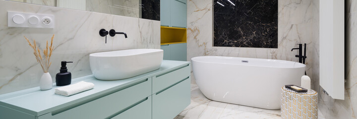 Elegant bathroom with bathtub and marble tiles, panorama