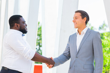 African-American businessman and his colleague in front of modern office building. Financial investors are talking outdoor. Banking and business concept.