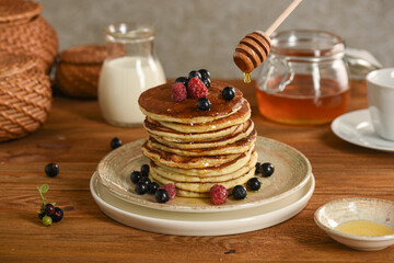 Pancakes are stacked and poured with honey.