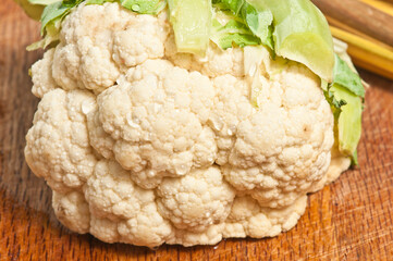 top view, close up of a head of cauliflower with leaves removed, on a wood cutting board