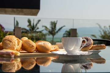 Outdoor afternoon tea, served in a white cup with bread on a background of palm trees, clear sky