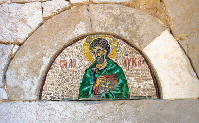 Close up of a mosaic with the image of the holy apostle Luke on an old stone orthodox church