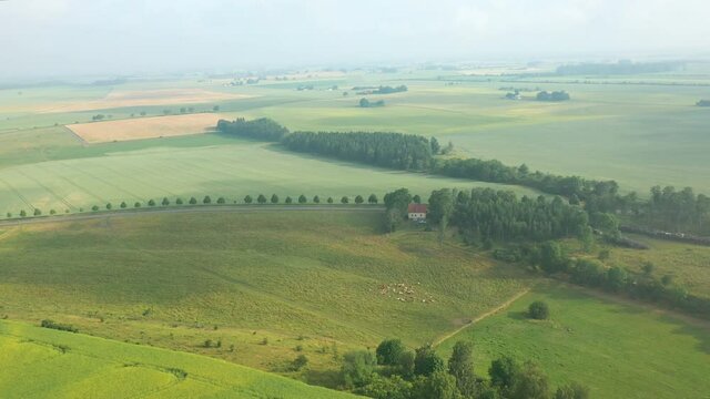 Aerial view of remote rural country landscape with green hills and meadows covered in sunshine and morning mist
