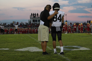 A high school football coach talks to a player