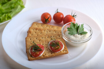Crispy cracker with herbs and cherries. Still life of eating cookies with sauce and herbs and tomatoes.