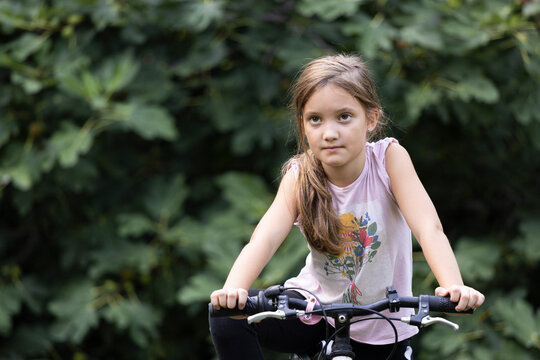 Beautiful young girl riding a bike in backyard