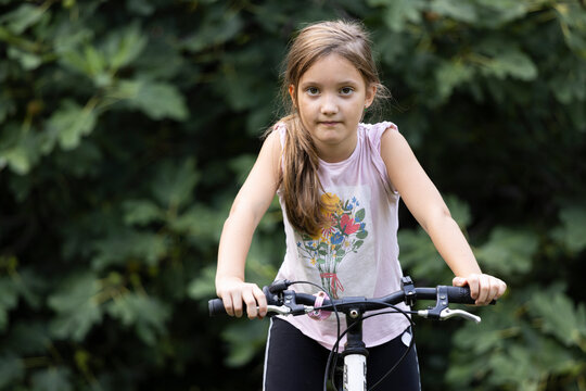 Beautiful young girl riding a bike in backyard