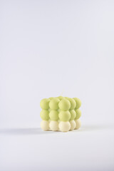 A pastel yellow and green bubble candle on a white background