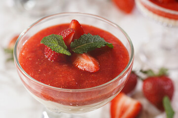 A glass of traditional italian creamy pudding dessert panna cotta with peppermint, strawberry jam,...