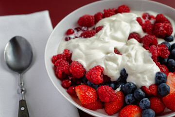 Red berry fruits and blueberries with yogurt, served in a bowl