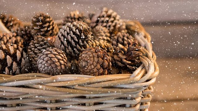 Animation of snow falling over pine cones in bascket