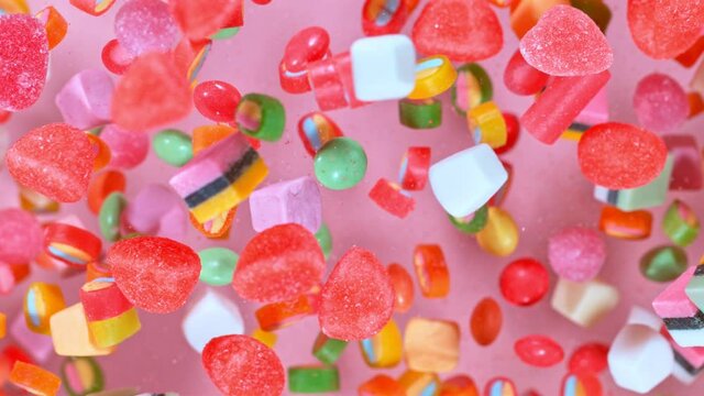 Sweet candies flying in slow motion against pastel background. Filmed on high speed cinema camera at 1000 fps.