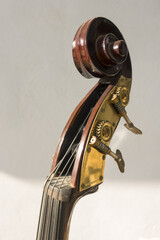 Closeup of a head and scroll and tuning pegs of a hand-carved Double bass