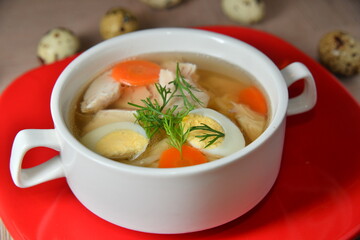 Chicken soup with egg and dill in the white bowl.