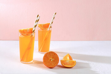 Modern still life with citrus fruits, orange juice and ingredients on a colored pink background...