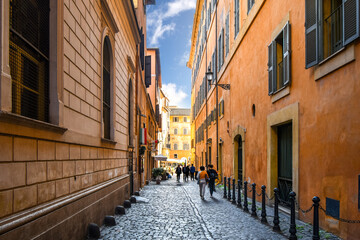 A colorful cobbled alley leading to a small piazza with outdoor cafe in the historic, centro storico section of Rome, Italy. 