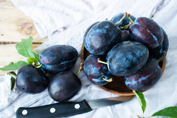 ripe sweet blue plums in a wooden plate