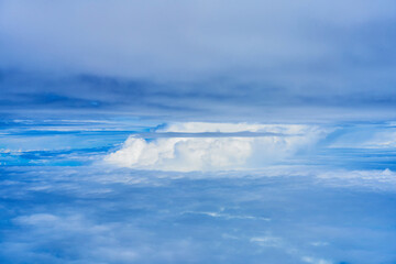 Landscape of fluffy white clouds on a dark blue sky. View from the plane at high altitude