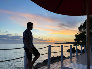 Silhouette of a young man looking at the sunset in a tropical beach