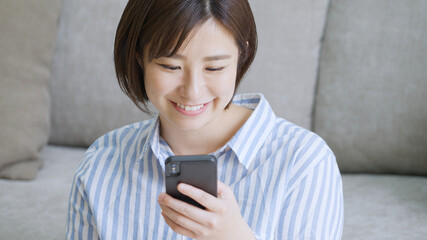 リビングでスマホを見る若い女性