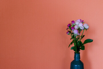 オレンジ色の壁背景のガラス瓶に活けたバラ