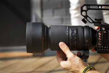 hand holds a long camera lens close-up of the photographer