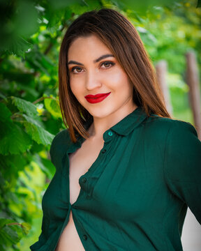 Closeup shot of a girl in a green shirt posing in front of trees