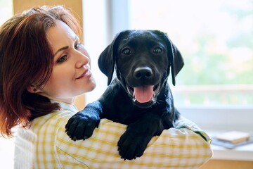 Portrait of middle aged woman and black labrador puppy dog © Valerii Honcharuk