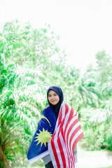 Muslim woman happy holding a Malaysian flag. Malaysia Independence Day.