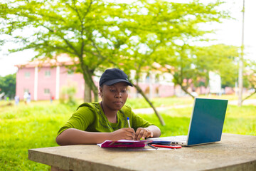 pretty african student feeling excited as she is working her assignment in the campus