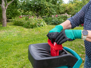 Hands lower old branches into a chopping and composting machine