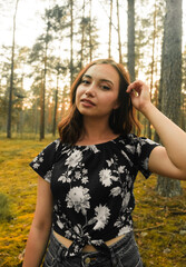 A young happy girl smiles against the background of the forest. High quality photo