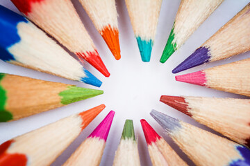 group of coloured pencils arranged in a circle with the tips pointing inwards, selective focus on the tips, horizontal, back to school concept