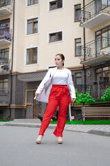 business woman in red pants, white blouse and jacket walking by the street