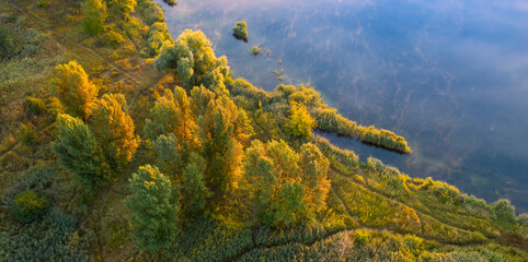 A small island on the lake with yellow autumn trees.