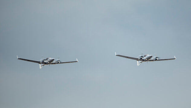 Small two twin-engine propeller military reconnaissance aircraft on a background of sky.