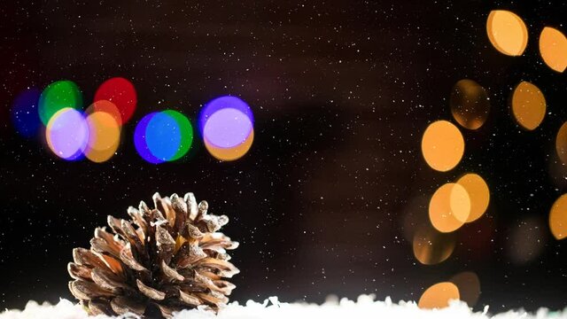 Animation of snow falling over pine cone and colorful bokeh