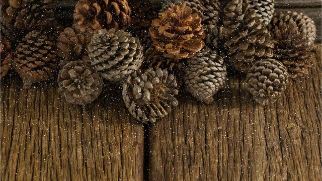Animation of snow falling over pine cones on wood board