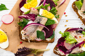 Pickled Marinated Herring and Beetroot Open Sandwich on Rye Bread. Traditional Danish Smorrebrod on White Background. Selective focus.